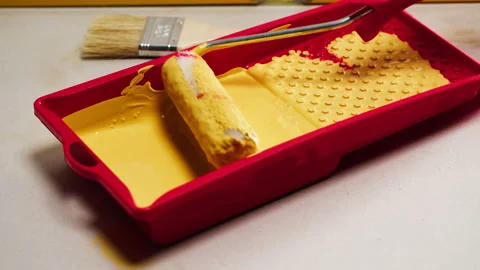 Dipping roller into yellow paint in plastic bath. Texture of gouache close-up Stock Footage 166577058