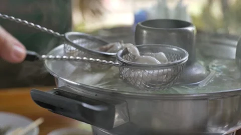Dipping slice of fish in metal strainer into boiled soup. Stock Footage 197394962
