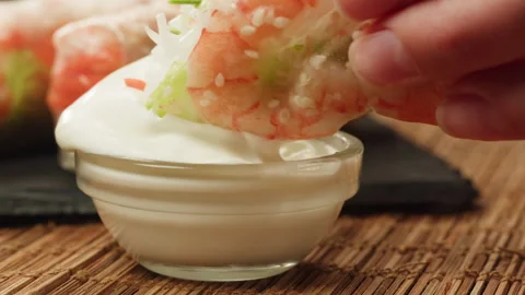 Dipping spring roll with shrimps and vegetables in white sauce close-up macro Stock Footage 257591760