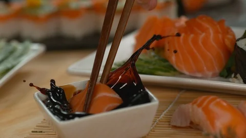 Close-up 4K slow-motion video of salmon sushi making. The sauce is