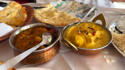 Dipping tasty coconut naan bread in Korma chicken dish sauce, Handi chicken Stock Footage 296579003
