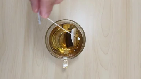 Dipping Tea Bag in Glass Mug of Hot Water Top View Stock Footage 346587394