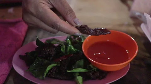 Dipping Thai Sun Dried Beef (Jerky) With Kaffir Lime Leaf In Red Chili Sauce Stock Footage 240450679