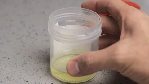 Dipping THC marijuana home test strip into urine sample cup, in bathroom at home Stock Footage 127553238
