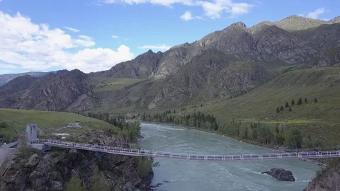 Direct aerial flight under mountain river Katun and suspension bridge. Altai Video stock 84596986