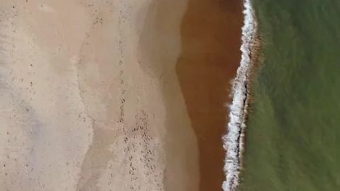 A direct overhead view of waves crashing onto beach. Stock Footage 155310503