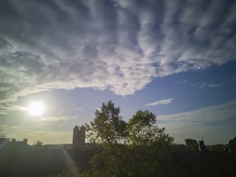 Direct sun sunset with clouds go behind a church tower and trees Stock Footage 168523638