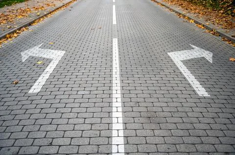 Direction arrows on paved road at intersection, choice concept Stock Photos