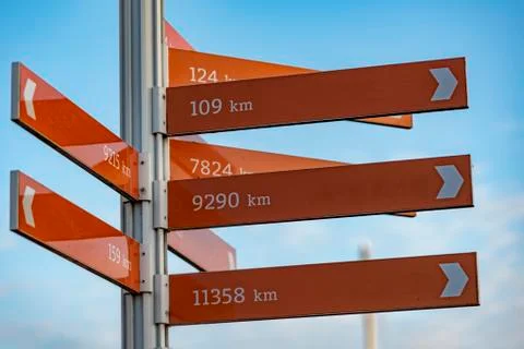 Direction pole indicating the direction of several cities and the distance fr Stock Photos