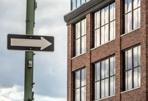 A directional arrow high on a light pole beside an office building Stock Photos