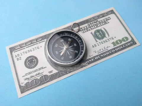 A directional pocket compass sits centered on a United States one hundred d.. Stock Photos