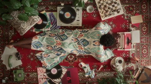 Directly Above of Author in Robe Lying on Rug, Typing on Vintage Typewriter Video stock 339851790