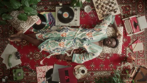 Directly Above of Black Man in Robe Relaxing on Retro Patterned Carpet Stock Footage 339851015