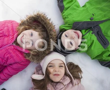 Directly Above Portrait Of Three Children (2-3, 4-5) Lying On Snow