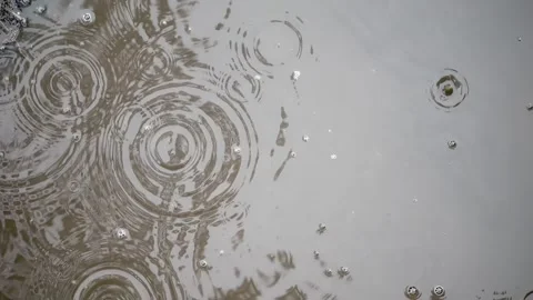 Directly above: Raindrops gently disturb puddle in slow-mo; bubbles rise, w.. Stock-Footage 255019483