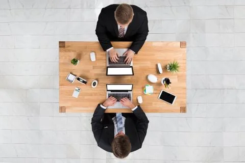 Directly above shot of businessmen using laptops at desk in office Stock Photos