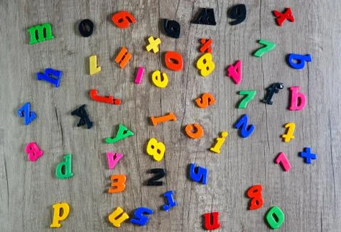 Directly above shot of multi colored  plastic numbers and  letters on  wooden Stock Photos