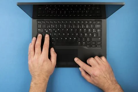 Directly above view of man using laptop computer on blue desk background 스톡 사진