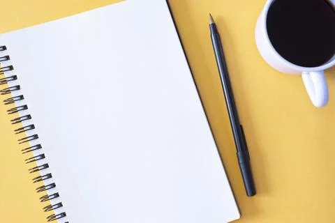 Directly above view of notepad, pen and coffee cup on yellow background. Foto stock