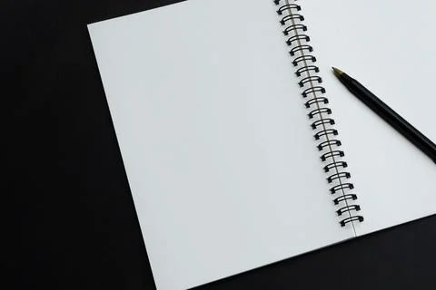 Directly above view of a pen with notepad on black background. Stock Photos