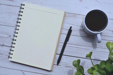 Directly view of notepad and pen with cup of coffee on wooden desk Stock Photos