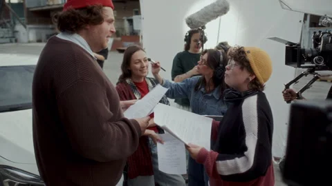 Director Discussing Script Details with Actors before Shoot on Outdoor Set Stock Footage 336700198