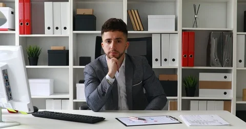 Director sitting at table in white office and putting hand to forehead Stock Footage 91283850