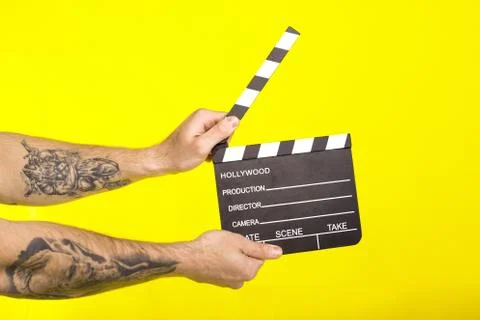 Director's clapper. hands with a board?lapper on a yellow background. Stock Photos