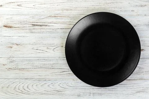 Directy above Empty black matte plate on white wooden background with copy sp Stock Photos