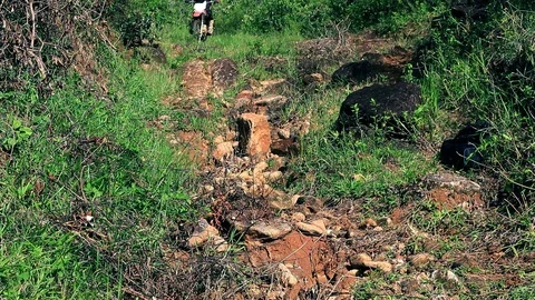 Dirt bike going down a trail with some big rocks Stock Footage 86694711