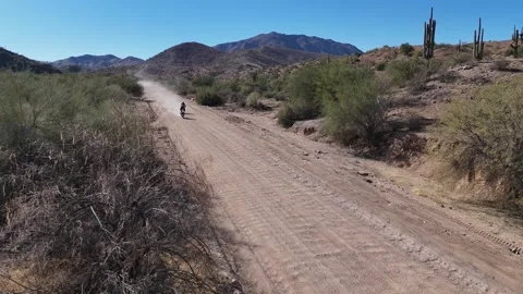 Dirt Bikes Riding down a Desert Road, kicking up dust behind them. Mountains Stock Footage 301162781