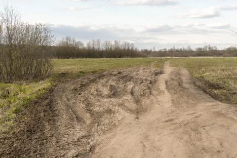 Dirt damaged rural spring road in a field. concept of problem with the roads Stock Photos