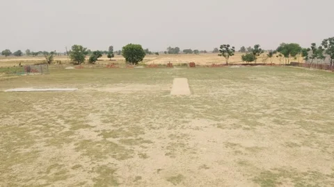 A dirt field with a cricket playground in the background Stock-Footage 256972486