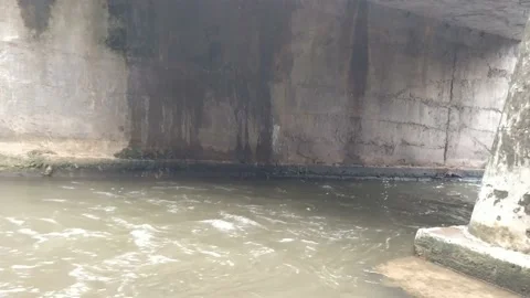 Dirt flood water flowing below the bridge Stockbeeldmateriaal 136896403