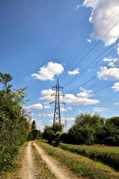 Dirt path bordered by a stream of water with an electricity pylon in the ital Stock Photos
