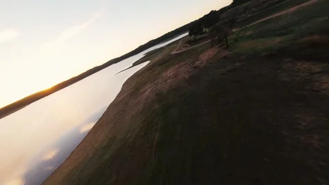 Dirt path curves beside quiet lake at golden hour at Pego do Altar Reservoir Stock Footage 342164156