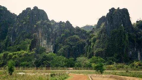 Dirt path with green fields and luxurious mountain in the background, Thakh.. Stock-Fotos