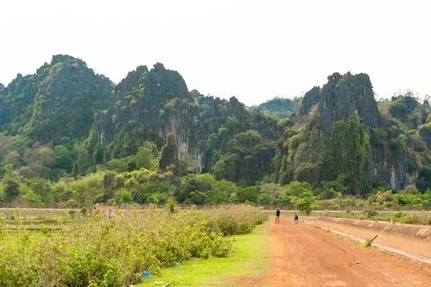 Dirt path with green fields and luxurious mountain in the background, Thakh.. Stock Photos
