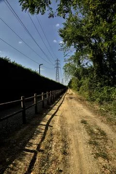 Dirt path partly in the shade casted by a hedge and split by a wooden fence i Stock Photos