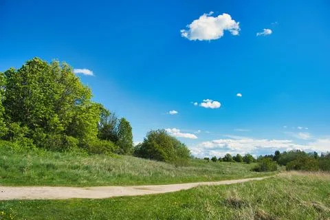 Dirt Path Through Green Meadow Under Blue Sky Stock Photos