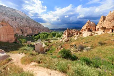 A dirt road meanders between conical peaks of rocks, ancient caves against th Stock Photos