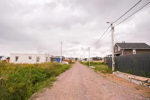 Dirt road through a developing village with new houses and construction, Foto stock