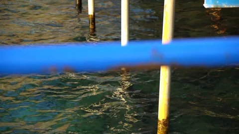 Dirty and rusty iron ladder leading down into milky blue water Stock Footage 95148920