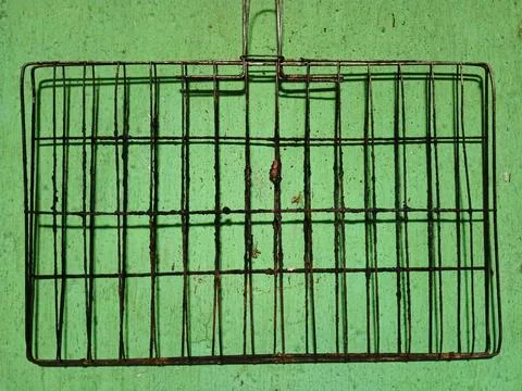 Dirty and rusty wire grilling basket on a green wall 스톡 사진