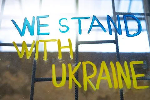 A dirty barred window on which is drawn in blue and yellow colours. We stand Stock-Fotos