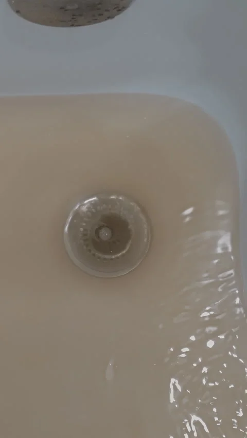 Dirty, brown, and polluted tap water swirling and creating a vortex as it Stock Footage 346185054