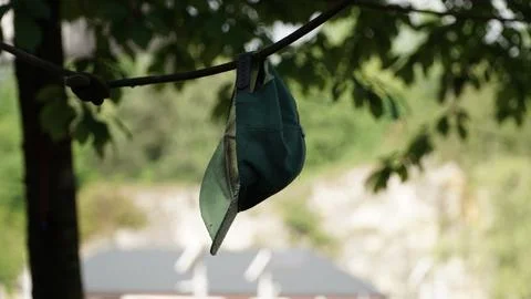Dirty Cap Hanging on a Clothesline Between Trees with Blurred Background Stock Photos
