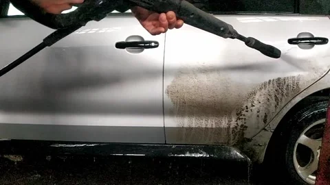 A dirty car is cleaned with a high-pressure jet of clean water by a car washer. Stock Footage 171052238