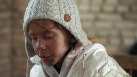 Dirty Child in White Jacket Wearing Wool Hat Looking Focused While Speaking Video stock 327350527