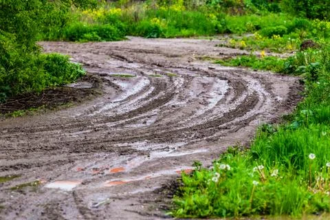 Dirty clay mud road zig-zag with puddles and tire tracks - closeup with Photos